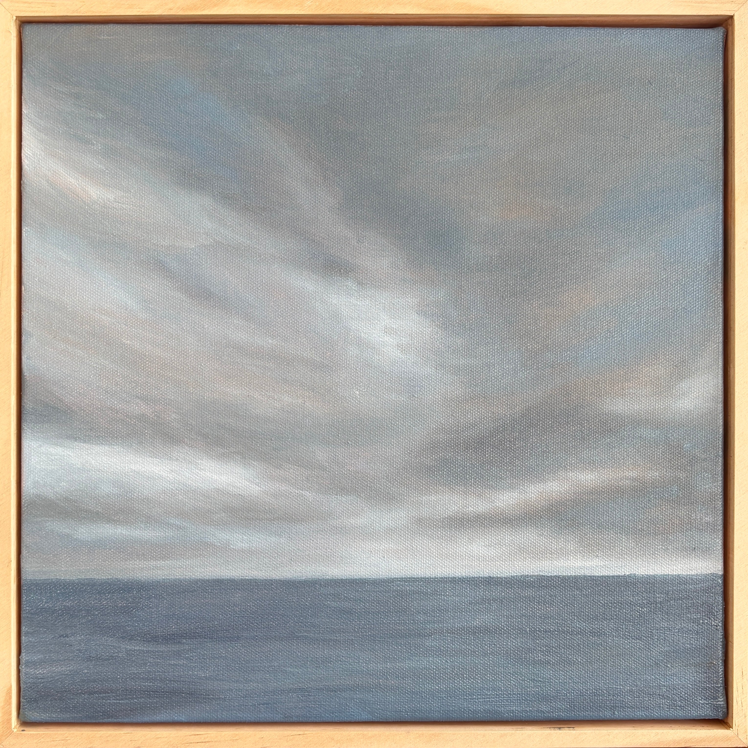 Painting of a cloudy sky over water with a wooden frame.